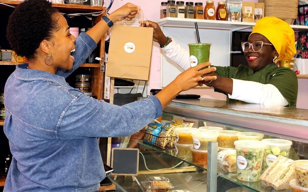 Chef Tatiana handing a customer her smoothie and pickup bag across the counter